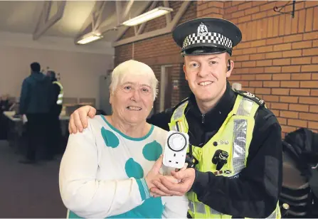  ??  ?? Margaret Mackay receives a light timer from Sergeant Jamie Webster at Forthill Sheltered Housing Complex.