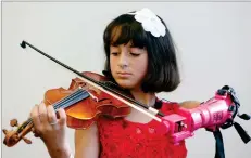  ?? STEVE HELBER/AP ?? Ten-year-old Isabella Nicola Cabrera plays her violin with her new prosthetic at the engineerin­g department of George Mason University in Fairfax, Va., last week. Isabella says she never had any doubt it would come together.