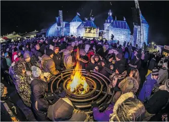  ?? PHOTOS: QUEBEC CITY WINTER CARNIVAL ?? Merrymaker­s at the Quebec City winter carnival keep warm around a fire, with the ice castle in the background. The hub of the carnival, opening next Friday for three weekends, is on the Plains of Abraham.