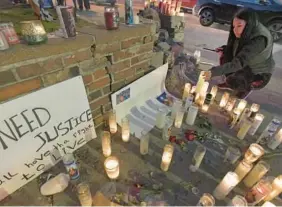  ?? AMY DAVIS/BALTIMORE SUN ?? Petra Anzures, a friend of Kevin Torres, lights candles at a vigil outside ChrisT Bar in Baltimore Highlands, where Torres was fatally shot by a security guard early on Nov. 7. Latino residents have been protesting at nightly vigils at the corner of East Lombard and South Haven streets for Torres, 35, president and coach of the Villanueva soccer team.