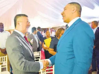  ??  ?? Prime Minister Andrew Holness (right) exchanges pleasantri­es with China’s Ambassador to Jamaica Tian Qi.