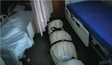  ??  ?? Una persona durmiendo en un hospital de Barcelona junto a un cuerpo sin vida sellado en bolsas