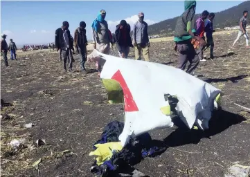  ??  ?? People walk past a part of the wreckage at the scene of the Ethiopian Airlines Flight ET 302 plane crash. — Reuters photos