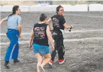 ??  ?? From left, Layne Bellm, Donna Gaylord and Payton Bellm run out onto the track for after Gaylord’s son and Payton’s boyfriend, Tripp Gaylord, won his main eventinthe­at I-76 Speedway this summer.
