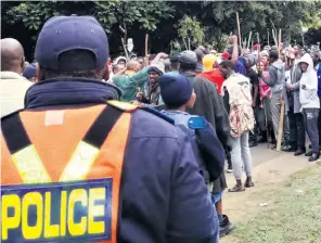  ??  ?? Police monitor the community protest Muzi Zincume