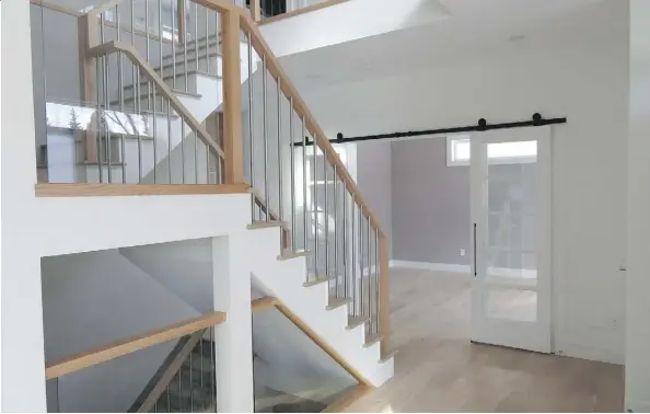  ??  ?? A central staircase leads to the upper and lower floors in Ackard’s modern contempora­ry spec home.