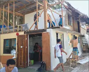  ??  ?? This handout photo received yesterday shows workers repairing a building damaged by Typhoon Phanfone, next to Bulabog beach on the island of Boracay.