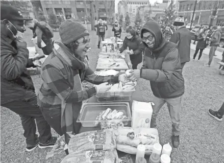  ?? PHOTOS BY MIKE DE SISTI /MILWAUKEE JOURNAL SENTINEL ?? Peoples Revolution organizer Mariah Smith, left, serves a burger to Payton, who only wanted to use his first name, as part of the Peoples Revolution marking its 200-plus day of action at Cathedral Square Park along East Wells Street in Milwaukee on Saturday.