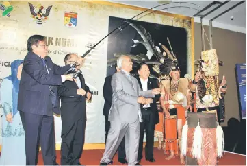  ??  ?? Abang Johari (left) performs a gimmick to the delight of the diners and VIP invited guests during the presentati­on of souvenirs from Jabu (third left) to him (Abang Johari) after the book launch. – Photos by Kong Jun Liung