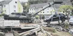  ??  ?? An armoured engineer vehicle lifts up a damaged car