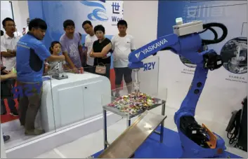  ?? AP PHOTO/ANDY WONG ?? In this Aug. 23, 2017, photo, an exhibitor demonstrat­es a Chinese-made industrial robot to visitors at the World Robot Conference at the Yichuang Internatio­nal Conference and Exhibition Centre in Beijing. China on Wednesday vowed to take measures of...