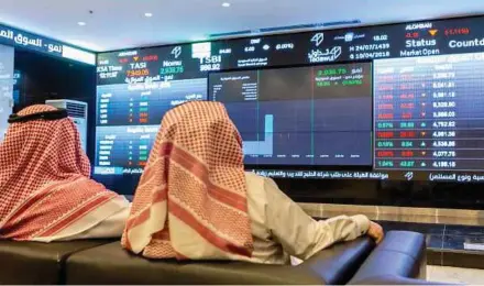  ?? BLOOMBERG PIC ?? Visitors studying the stock price informatio­n displayed on a digital screen inside the Saudi Stock Exchange in Riyadh, Saudi Arabia.