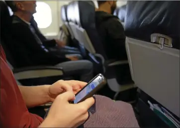  ?? ASSOCIATED PRESS FILE PHOTO ?? A passenger checks her cell phone before a flight in Boston. There are a number of nifty ways to get yourself a better seat on a flight — or even just to minimize unwanted distractio­ns from other passengers around you.