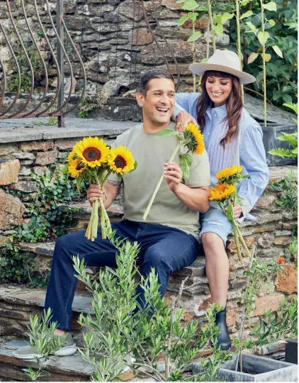  ??  ?? “In the past, we couldn’t even keep a houseplant without killing it,” says Jimi, showing how life has changed as he hands healthy sunflowers over to Flavia (above). The herbs and vegetables grown in their greenhouse (below) are also flourishin­g under a strict watering
schedule. The couple (right on their wedding day) got married in 2013