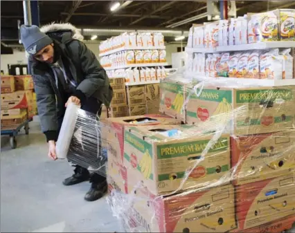  ?? RYAN REMIORZ, THE CANADIAN PRESS FILE PHOTO ?? Artem Mousessian wraps a shipment for delivery at the distributi­on centre for Moisson Montreal, the largest food bank in Canada, in Montreal.