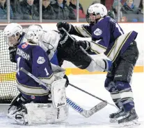  ?? KEITH GOSSE/THE TELEGRAM ?? Daniel Penney of the Gonzaga Vikings (right) pushes Michael Gill of the Mount Pearl Senior High Huskies towards the net and Gonzaga goaltender Liam Buckingham during Confederat­ion Cup high school hockey action at the Goulds Arena Sunday afternoon.