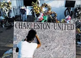  ?? JOE RAEDLE/GETTY ?? Jennice Barr, 10, writes a message Monday on a board set up in front of Emanuel African Methodist Episcopal Church where nine people were slain last week in Charleston, S.C.