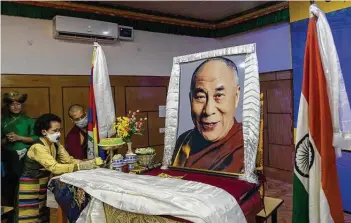  ??  ?? An exile Tibetan offers a piece of cake to a portrait of her spiritual leader the Dalai Lama to mark her leader’s 85th birthday in Dharmsala, India on Monday.