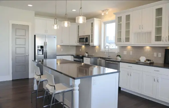  ?? PHOTOS: JENNIFER JACOBY-SMITH ?? The grey quartz countertop and pale grey subway tiles are a modern hit. The tradition farmhouse style apron sink gets a modern update in stainless steel.