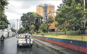  ?? Miguel Gutierrez For The Times ?? JOSE CAICEDO takes food and clothing that sister Tere shipped from Los Angeles to a home for low-income retirees in Caracas. The Caicedo family keeps some necessitie­s and gives away what it doesn’t need.