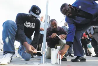  ?? Mel Melcon / TNS ?? Los Angeles residents light candles during a prayer vigil and moment of silence at the intersecti­on of Florence and Normandie — ground zero of the unrest in 1992.