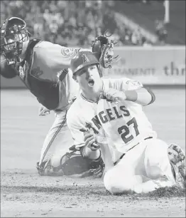  ?? Jeff Gross Getty Images ?? MIKE TROUT (27) delivers the Angels’ second run, beating Baltimore catcher Matt Wieters’ tag to score on Torii Hunter’s double in the seventh inning.