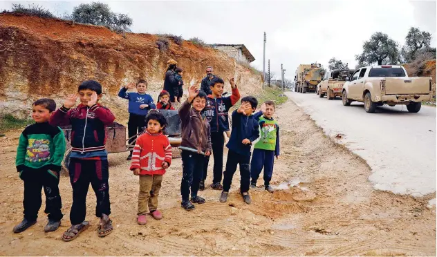  ?? Agence France-presse ?? Children watch as a military convoy crosses into the Syrian territory via the Kafr Lusin border in Idlib on Saturday.
