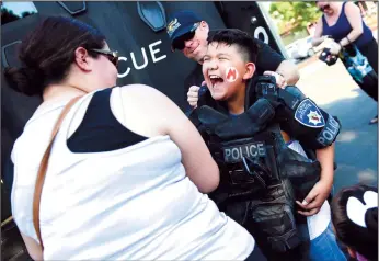  ?? NEWS-SENTINEL FILE PHOTOGRAPH­S ?? Julian Hernandez of Lodi enjoys trying on the heavy vest worn by members of the SWAT team during National Night Out in Lodi Tuesday Aug. 1, 2017.