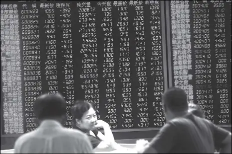  ?? EPA ?? Chinese investors sit in front of a big screen showing stock market movements in a securities brokerage house in Beijing.