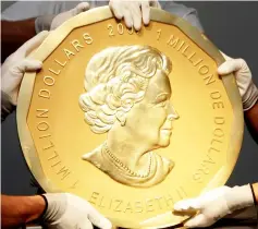  ??  ?? File photo shows experts of an Austrian art forwarding company holding one of the world’s largest gold coins, a 2007 Canadian US$1,000,000 ‘Big Maple Leaf’.