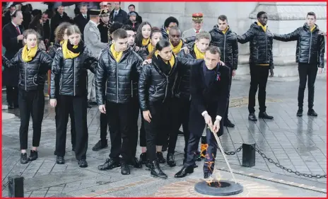  ?? AP ?? French President Emmanuel Macron links with children at the Tomb of the Unknown Soldier under the Arc de Triomphe