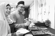  ??  ?? Abdul Mutalib (second left) serves his guests at Bomba’s Ramah-Tamah Aidilfitri in Sungai Merah station.