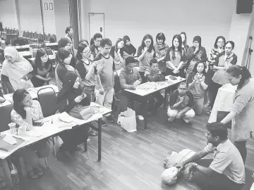  ??  ?? Dr Prem (right, sitting on floor) demonstrat­es first aid treatment to participan­ts.