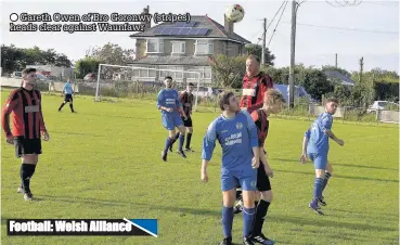  ??  ?? Gareth Owen of Bro Goronwy (stripes) heads clear against Waunfawr