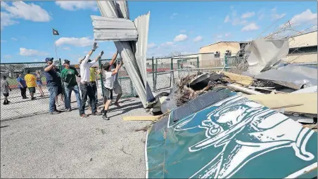  ?? [ERIC GAY/THE ASSOCIATED PRESS] ?? Coaches and students at Rockport-Fulton High School in Rockport, Texas, help clear the debris that Hurricane Harvey left on their football field.