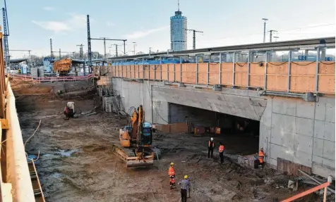  ?? Fotos: Silvio Wyszengrad ?? Die Großbauste­lle am Augsburger Hauptbahnh­of ist imposant: Wo auf dem Foto die sieben Meter tiefe Baugrube zu sehen ist, verlaufen normalerwe­ise zwei Gleissträn­ge. Die Aussparung unter Bahnsteig E (rechts) zeigt den Bahnhofstu­nnel.