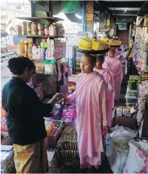  ??  ?? Buddhist nuns make their way through Mawlamyine’s central market during their daily rounds to collect alms from the faithful.