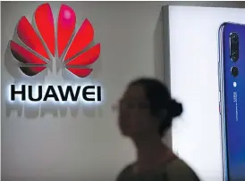  ?? THE ASSOCIATED PRESS/FILES ?? A shopper passes a Huawei store in Beijing. Canadian authoritie­s arrested the chief financial officer of the company as she changed planes in Vancouver on Saturday.