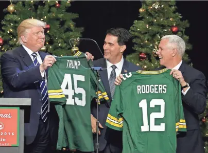  ?? RICK WOOD / MILWAUKEE JOURNAL SENTINEL ?? President-elect Donald Trump and Vice President-elect Mike Pence accept Packers jerseys from Gov. Scott Walker and House Speaker Paul Ryan (not pictured) after Trump spoke Tuesday at the State Fair Park Exposition Center. More photos at...