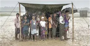  ?? — AFP ?? In this file photo taken on October 6, 2017, Rohingya Muslim refugees take shelter from the rain during a food distributi­on at Nayapara refugee camp in Bangladesh’s Ukhia district.