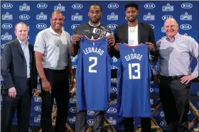  ?? RINGO H.W. CHIU - THE ASSOCIATED PRESS ?? Kawhi Leonard, center, and Paul George, second right, holding their jerseys, pose with Clippers president of basketball operations Lawrence Frank, left, head coach Doc Rivers, second left, and team chairman Steve Ballmer during a news conference in Los Angeles, on Wednesday.