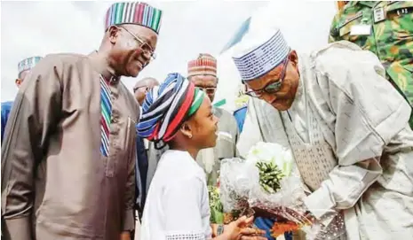  ??  ?? A little girl in Benue unity attire presents flowers to the president on his arrival at Makurdi airport