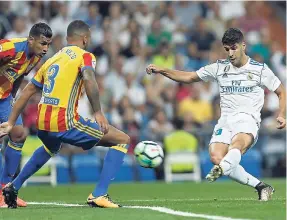  ?? AP ?? Real Madrid’s Marco Asensio (right) scores the opening goal past Valencia’s Ruben Vezo (second left) during a Spanish LaLiga football match between Real Madrid and Valencia at the Santiago Bernabeu stadium in Madrid yesterday.