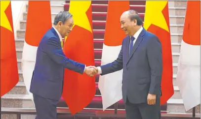  ?? Nhac Nguyen The Associated Press ?? Japan’s Prime Minister Yoshihide Suga, left, shakes hands with Vietnam’s Prime Minister Nguyen Xuan Phuc after the exchange of documents Monday at the Government Office in Hanoi.