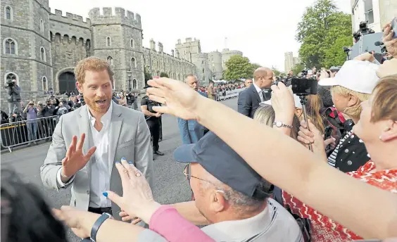  ?? AFP ?? Saludo a la gente. Los príncipes Harry y William, más atrás, ayer, en las puertas del Palacio de Windsor, saludando a sus seguidores.