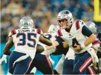  ?? GEORGE WALKER IV/AP ?? Patriots quarterbac­k Bailey Zappe hands off to running back Pierre Strong Jr. in the second half of Friday’s preseason game. The Patriots fell, 23-7.