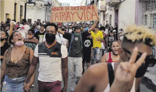  ?? ALEXANDRE MENEGHINI / REUTERS ?? Ciudadanos proclaman eslóganes contra el Gobierno cubano durante una protesta en La Habana, el domingo.