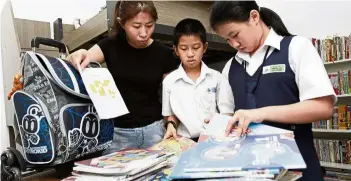  ??  ?? Back to school: Ooi with her son and daughter preparing their books to return to school at their home in George Town, Penang.