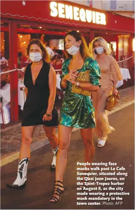  ?? Photo: AFP ?? People wearing face masks walk past Le Cafe Senequier, situated along the Quai Jean Jaures, on the Saint-Tropez harbor on August 8, as the city made wearing a protective mask mandatory in the town center.