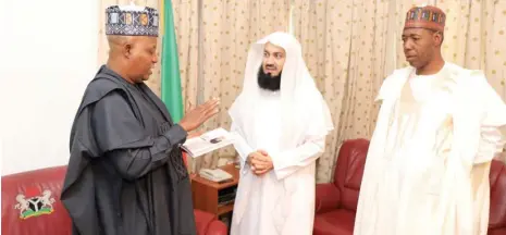  ??  ?? Famous Islamic Scholar from Zimbabwe, Sheikh Mufti Menk presents a copy of his book, ‘Motivation­al Moments’ to Governor Kashim Shettima of Borno State (left), at the Government House in Maiduguri on Tuesday afternoon. The Sheikh was in Maiduguri to deliver lectures at Al-Ansar Mosque and the University of Maiduguri.